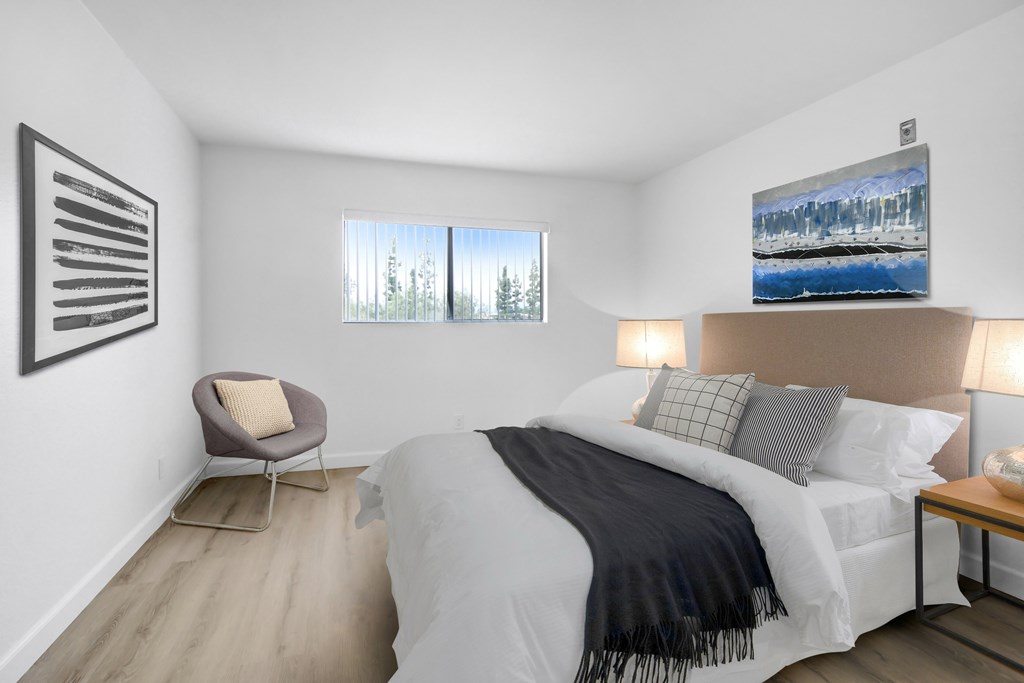 A bedroom with a large bed and a chair.