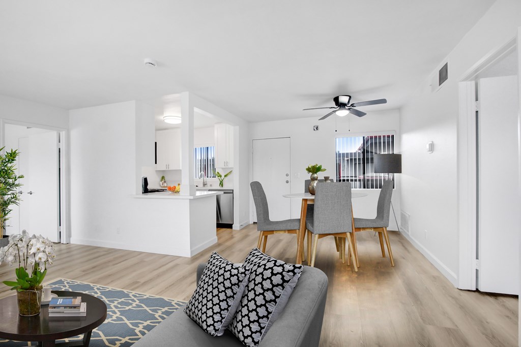 A modern living room with a grey sofa and wooden chairs.