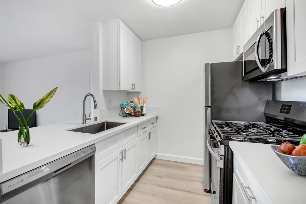 A modern kitchen with white cabinets and stainless steel appliances.