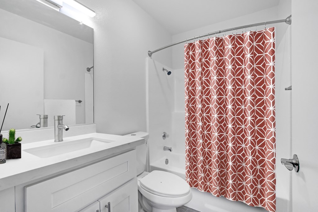 A bathroom with a white sink, toilet, and a red shower curtain.