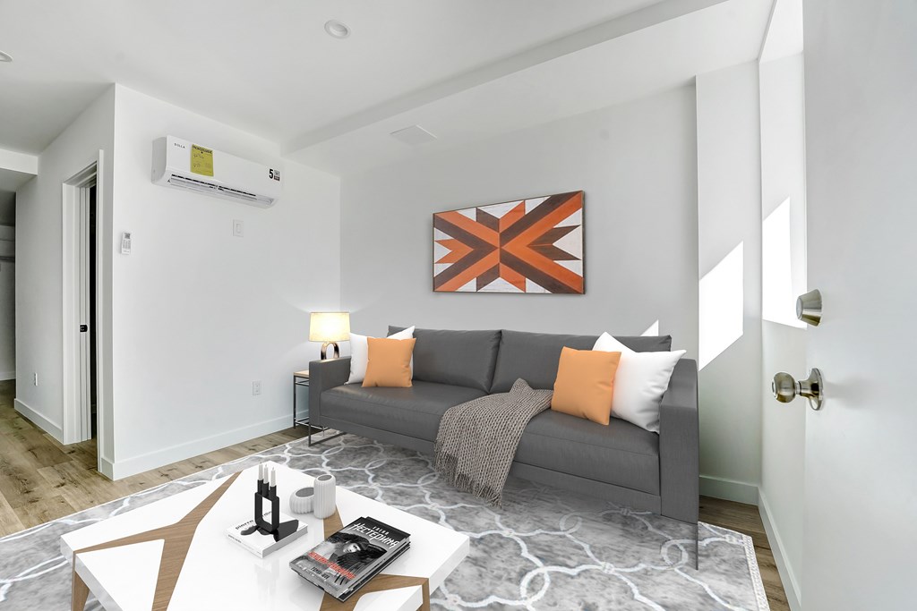 A living room with a grey couch and a painting on the wall.