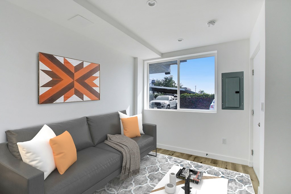 A living room with a grey couch and a large picture on the wall.