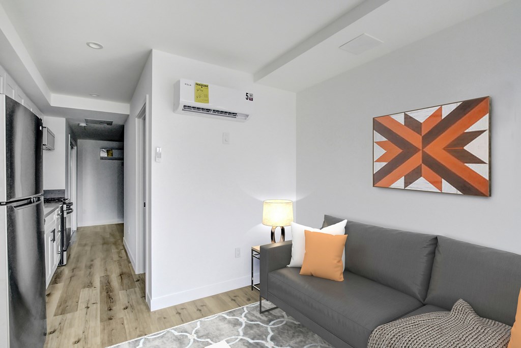 A living room with a grey couch and a painting on the wall.