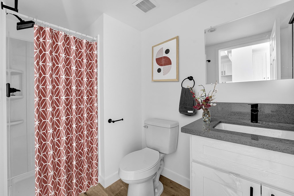 A bathroom with a toilet, sink, and shower curtain.