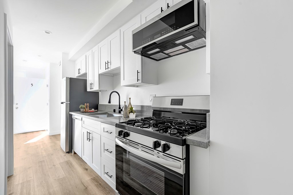 A modern kitchen with a black stove top oven and white cabinets.