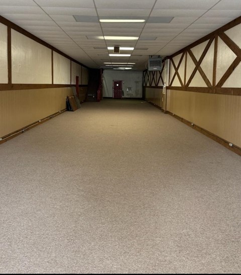 A long hallway with a carpeted floor and wooden walls.