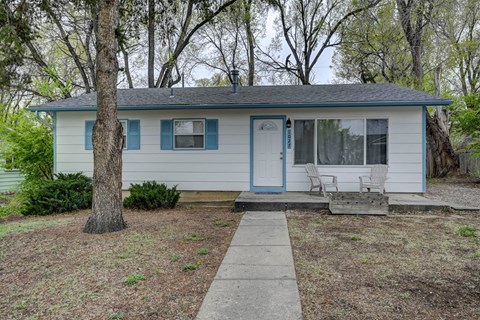 A small house with a blue door and white siding.