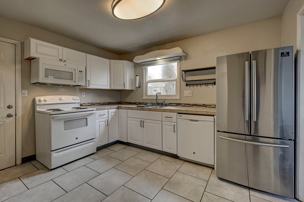 A kitchen with white appliances and cabinets.