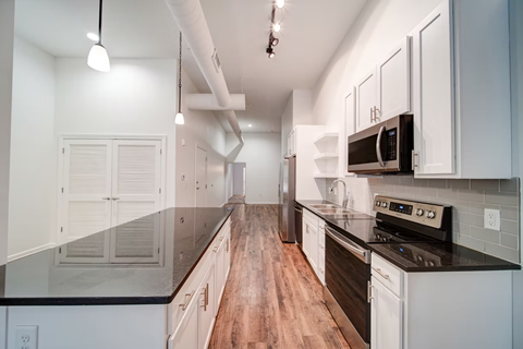 A modern kitchen with white cabinets and black countertops.