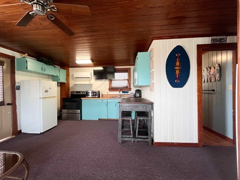A kitchen with a ceiling fan and a blue oval sign on the wall.