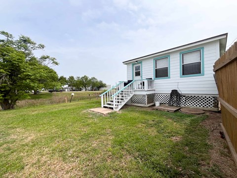 A small white house with a blue staircase and a wooden fence.
