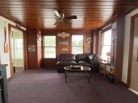 A living room with a brown ceiling and a black leather couch.
