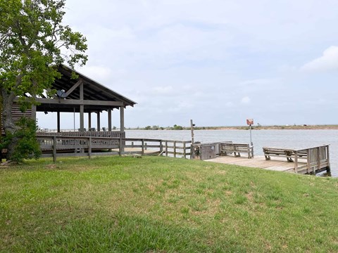 A gazebo sits on a grassy area next to a body of water.