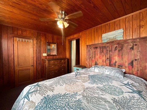 A bedroom with a bed, dresser, and ceiling fan.