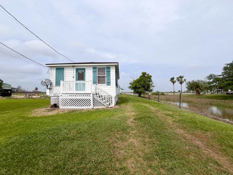 A white house with a porch and a green lawn.