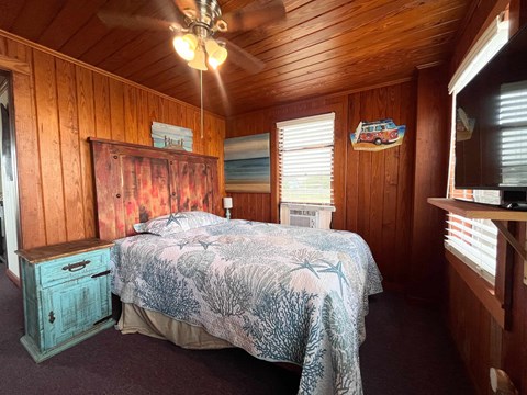 A bedroom with a bed, dresser, and ceiling fan.