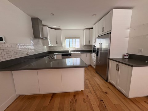 A kitchen with white cabinets and a black countertop.