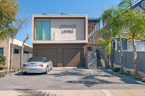 A car is parked in front of a building with the sign "ORANGE LAWN".