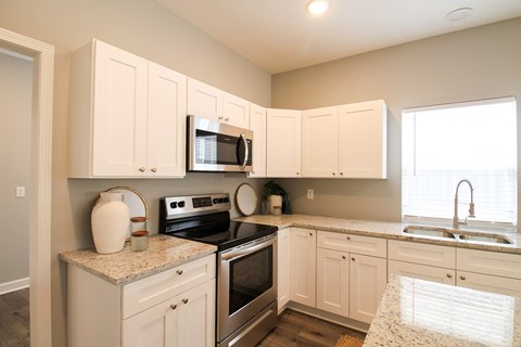 A kitchen with white cabinets and a granite countertop.