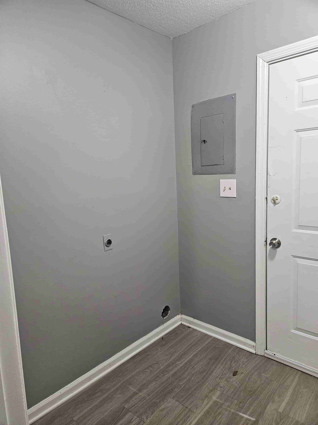 A white door is on the right side of a room with grey walls.