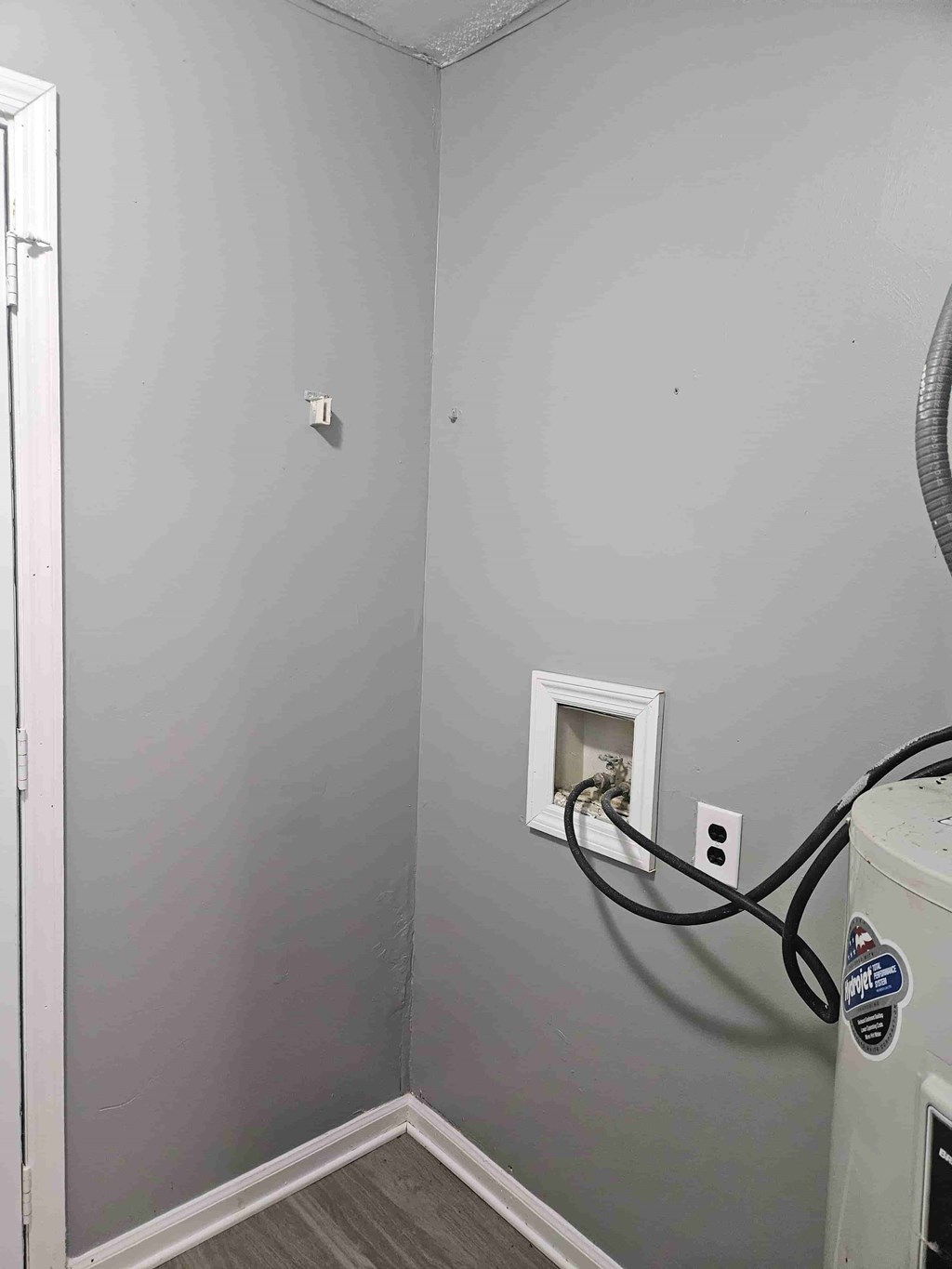 A wall socket with a black cord plugged into it.