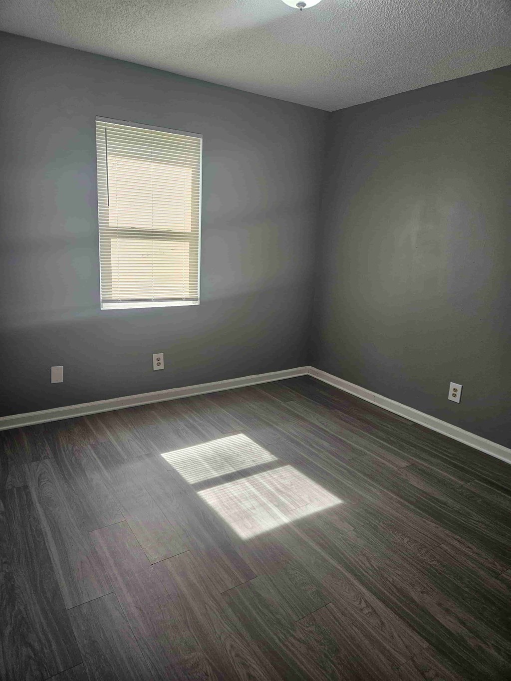 A room with a window and wooden flooring.