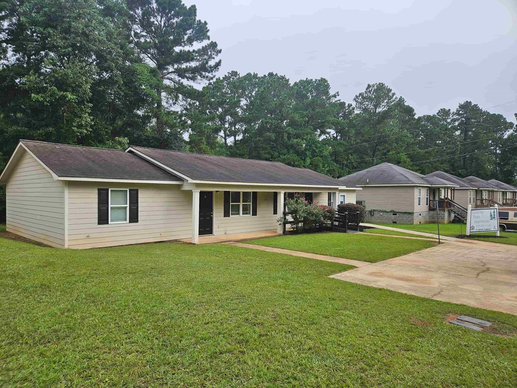 A house with a brown roof and a green lawn in front.