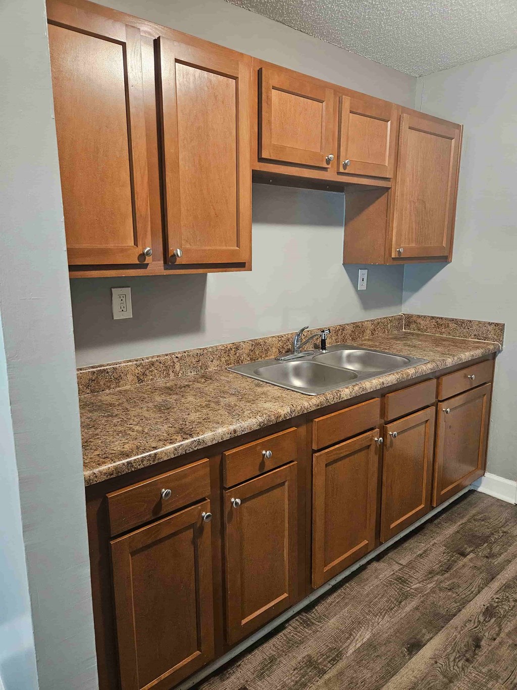 A kitchen with brown cabinets and granite countertops.