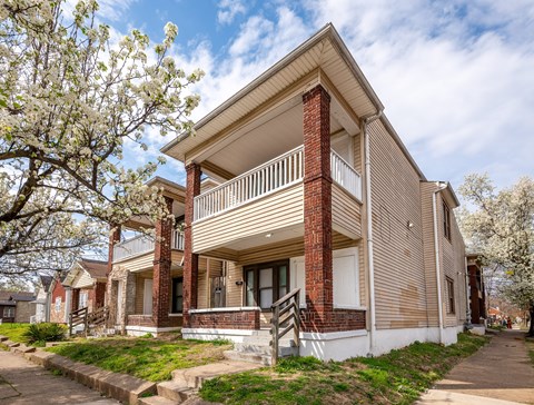 A two-story house with a balcony and a brick chimney.