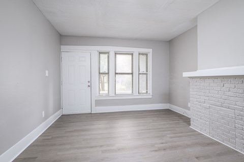 A room with a white door and a window with white curtains.