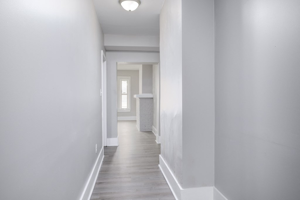 A long white hallway with a door at the end.