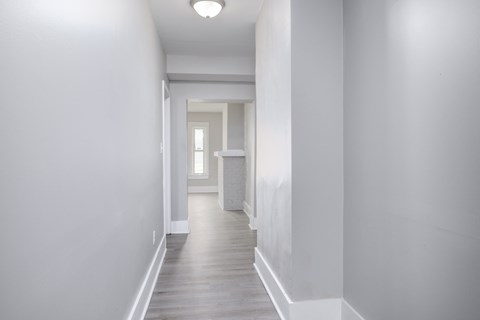 A long white hallway with a door at the end.