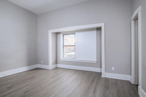 A room with a window and wooden flooring.