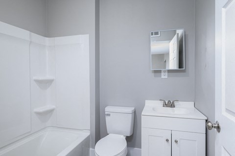 A white bathroom with a toilet, sink, and bathtub.
