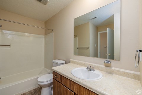 A bathroom with a sink, mirror, toilet and bathtub.