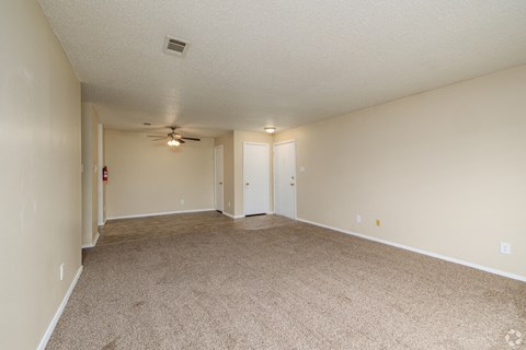 A room with a carpeted floor and a ceiling fan.