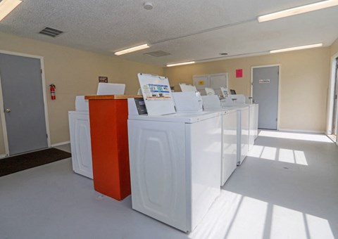A row of white and orange washing machines in a laundromat.