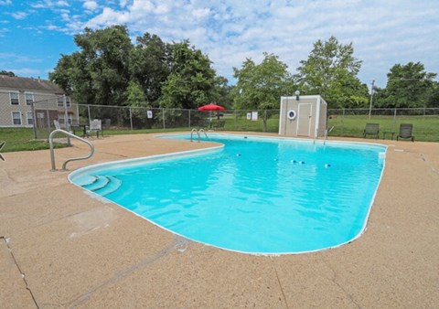 A small pool with a diving board and a small building next to it.