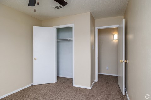 A room with a ceiling fan and three doors.