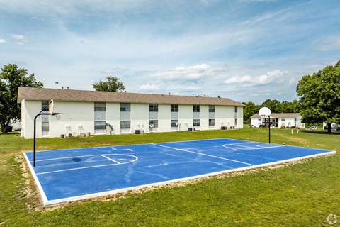 A basketball court in front of a white building.