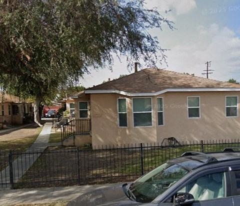 A beige house with a black fence in front.