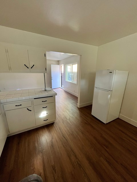 A kitchen with white cabinets and a white fridge.