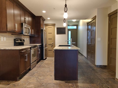 A kitchen with brown cabinets and a marble countertop.