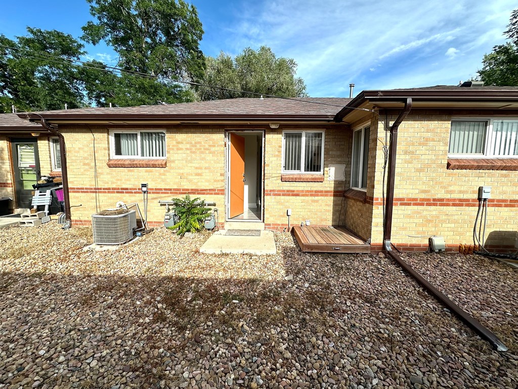 A brick house with a gravel driveway in front.