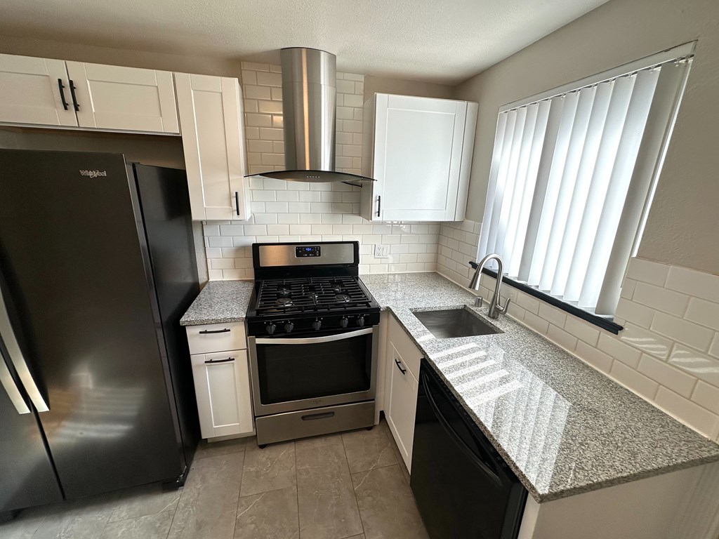A kitchen with a black fridge, stove, and dishwasher.