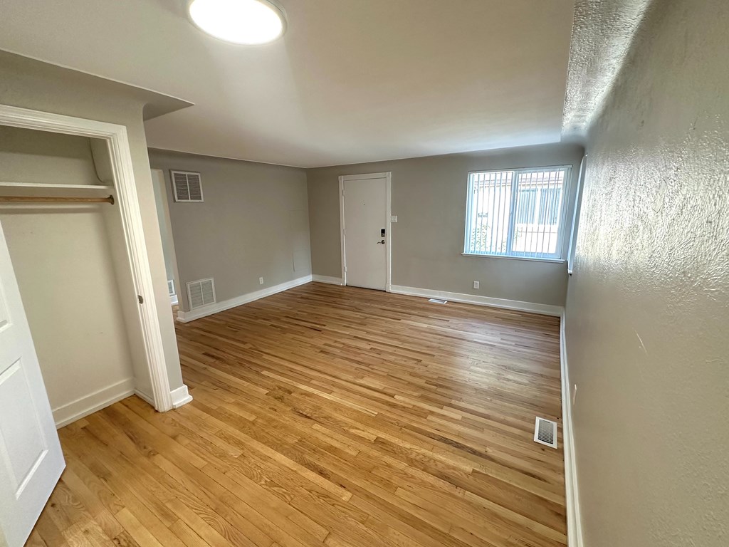 A room with wooden flooring and a window with blinds.