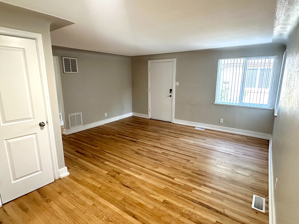 A room with wooden flooring and a window with blinds.