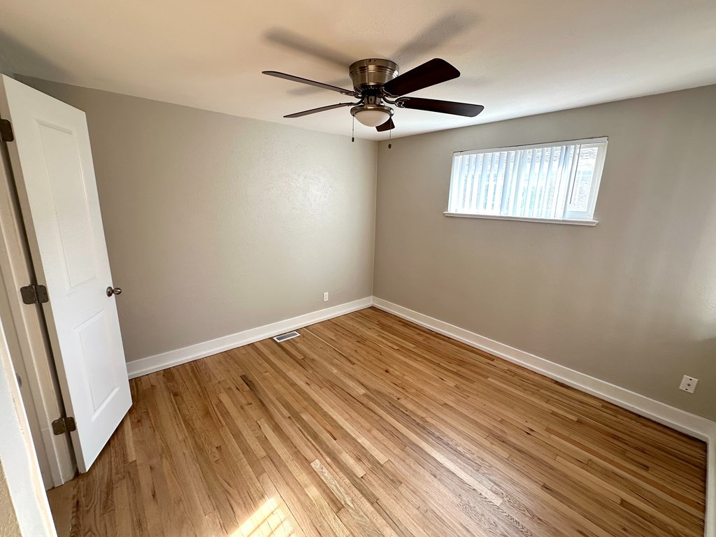 A room with a ceiling fan and a window with blinds.