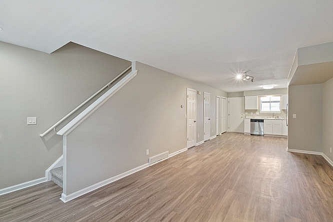 A spacious room with wooden floors and a staircase.