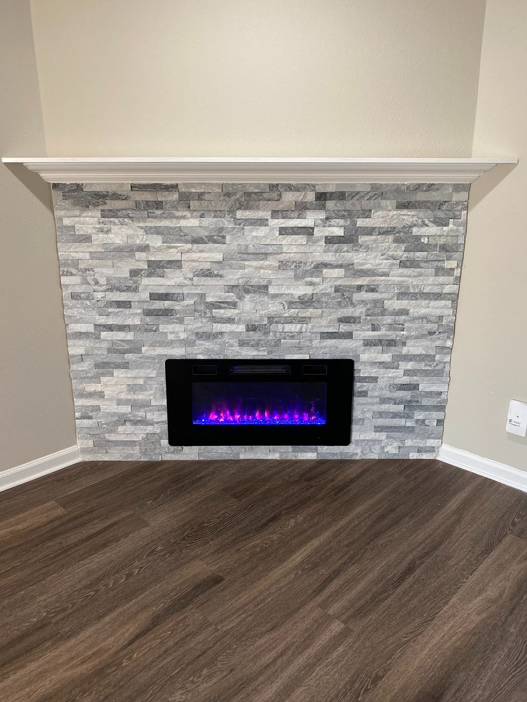 A modern fireplace with a stone facade and a lit fire.